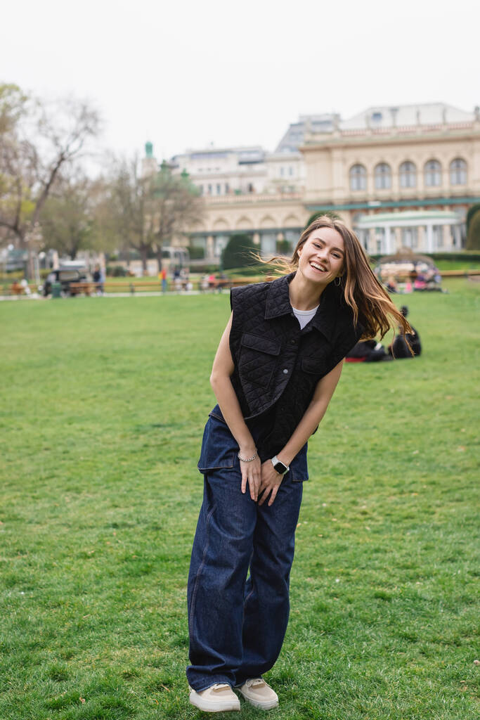 mladá veselá žena v bundě bez rukávů v zeleném parku Rakouska  - Fotografie, Obrázek