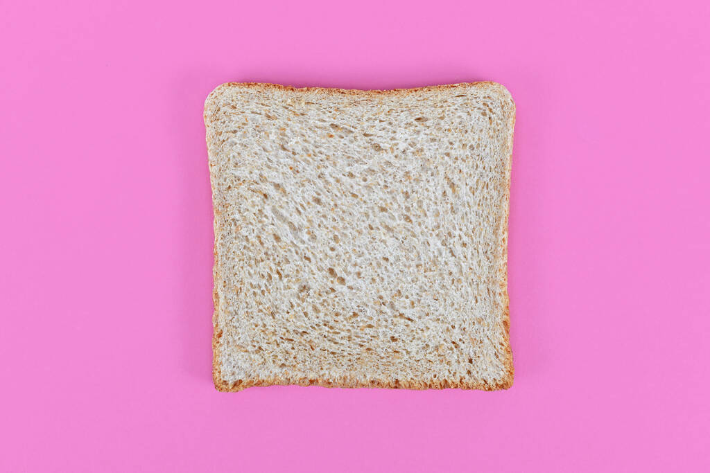 plakjes spelt tarwe toast brood op roze achtergrond - Foto, afbeelding
