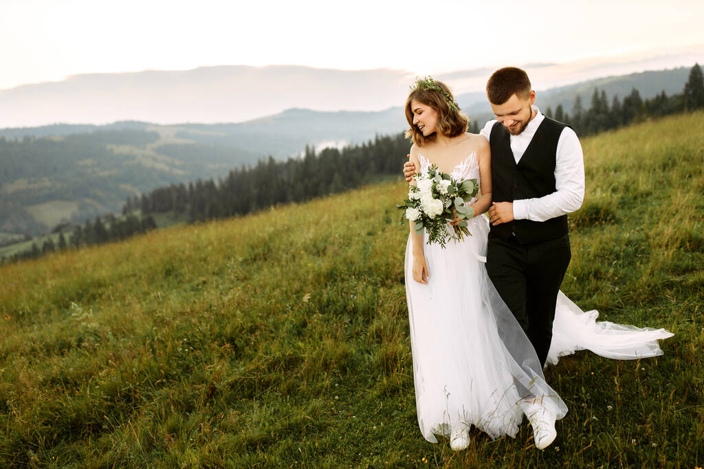 beautiful young wedding couple in love posing on the background of the mountains - Photo, Image