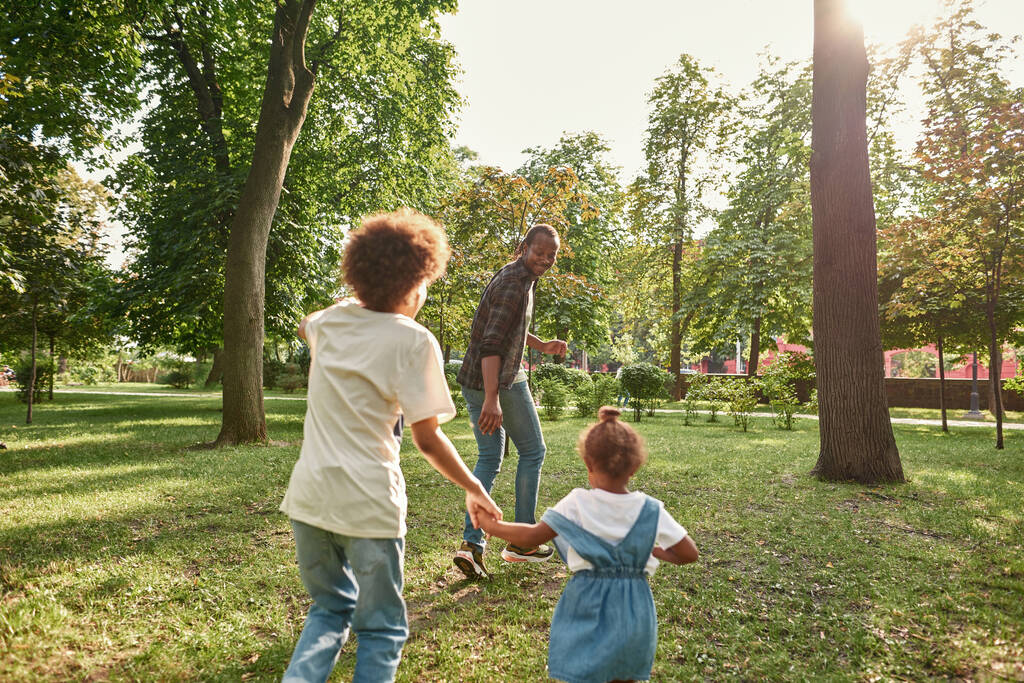 młody czarny rodzina grać na trawniku w słoneczny park - Zdjęcie, obraz