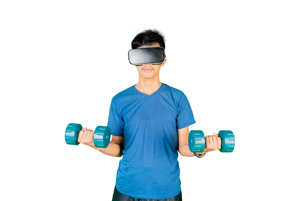 Jovem segurando dois halteres enquanto usava fone de ouvido VR no estúdio. Isolado sobre fundo branco - Foto, Imagem