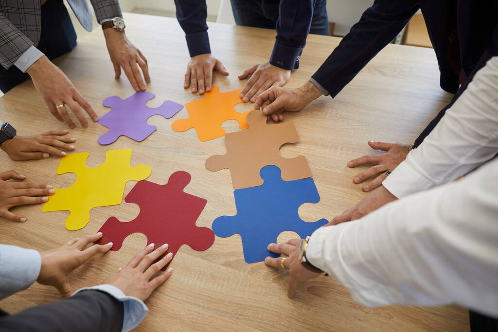 Team of business professionals trying to match colorful pieces of a jigsaw puzzle - Photo, Image