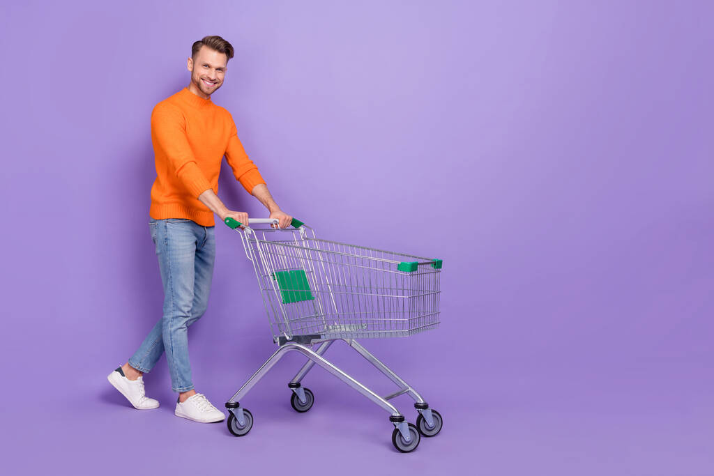 Full body photo of cheerful handsome man go shopping acheter des produits pour dîner romantique isolé sur fond de couleur violette - Photo, image
