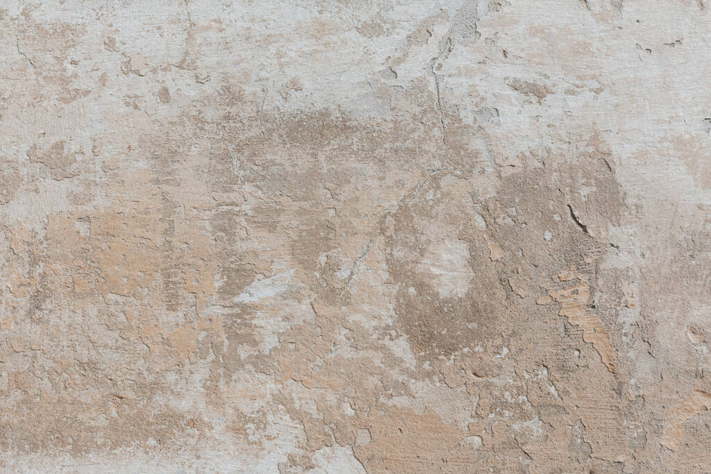 Plastered weathered wall with detailed texture. Grunge background in soft beige colors. A concrete surface with damages. - Photo, Image