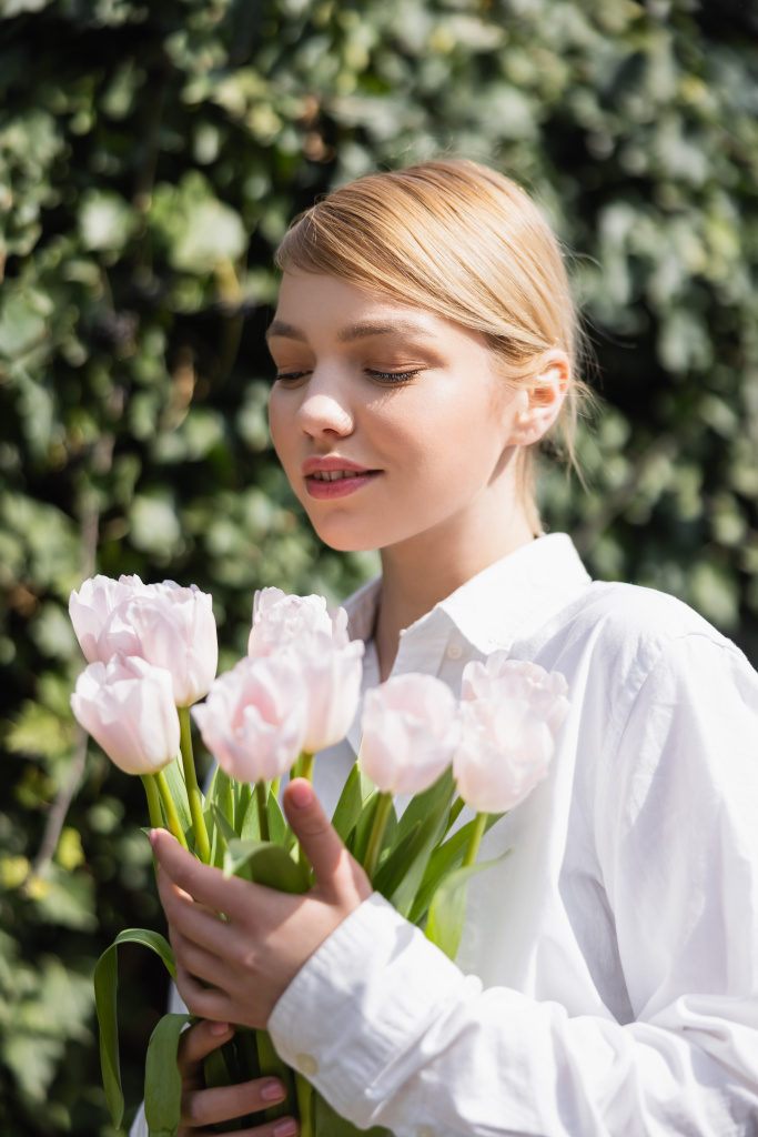 happy blonde woman holding white tulips on blurred background outdoors - Photo, Image
