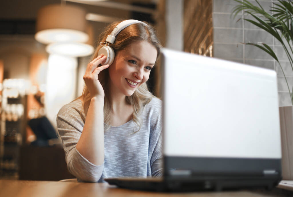 jovem mulher em um café com um computador e fones de ouvido - Foto, Imagem