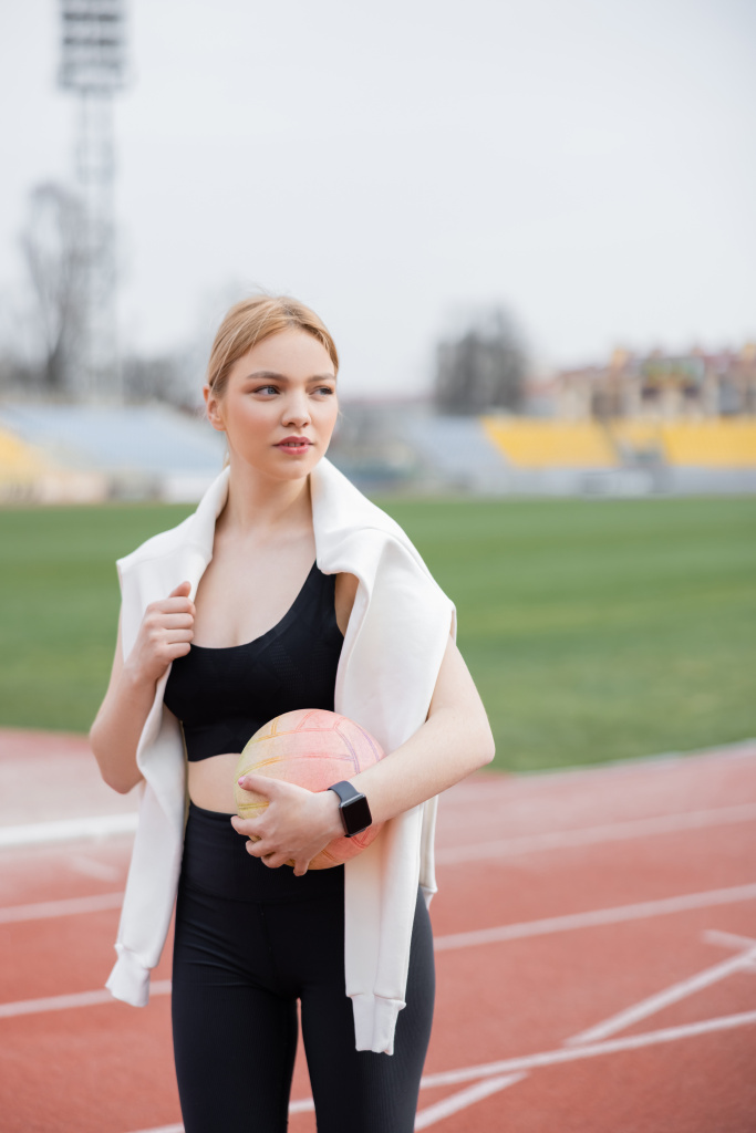 sportswoman holding ball while looking away outdoors - Photo, Image