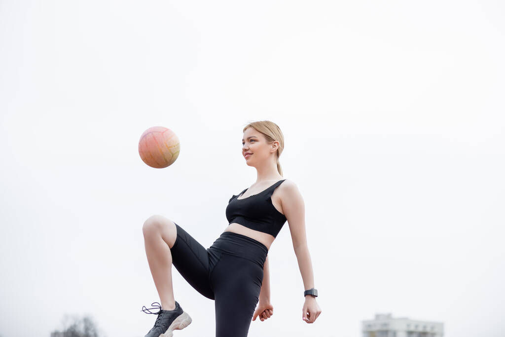low angle view of woman in black sportswear training with ball outdoors - Photo, Image