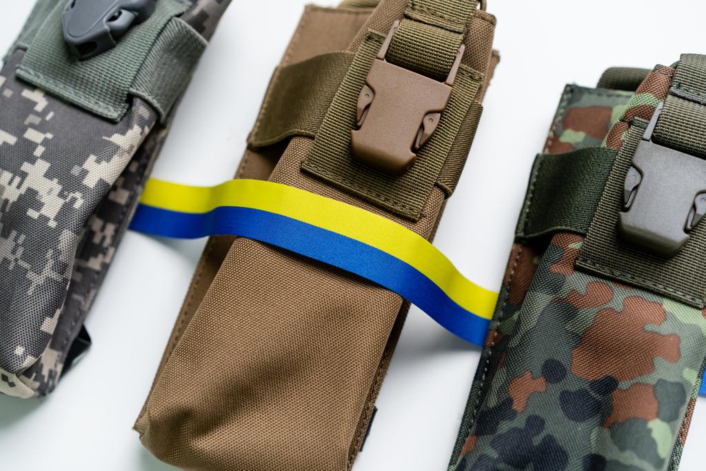 Beyaz arka planda askeri çantaların yanındaki mavi ve sarı kurdelenin üst görüntüsü - Fotoğraf, Görsel