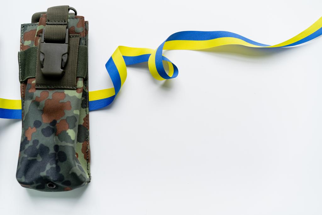 Vista superior da fita azul e amarela perto do saco militar no fundo branco - Foto, Imagem
