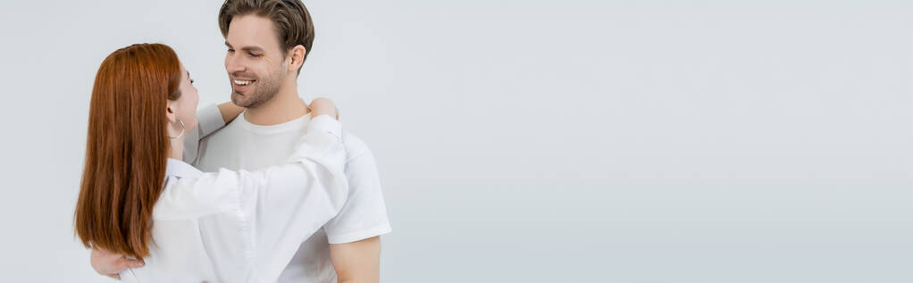 Νεαρή γυναίκα με πουκάμισο αγκαλιάζει χαμογελαστό φίλο απομονωμένο σε λευκό, λάβαρο  - Φωτογραφία, εικόνα