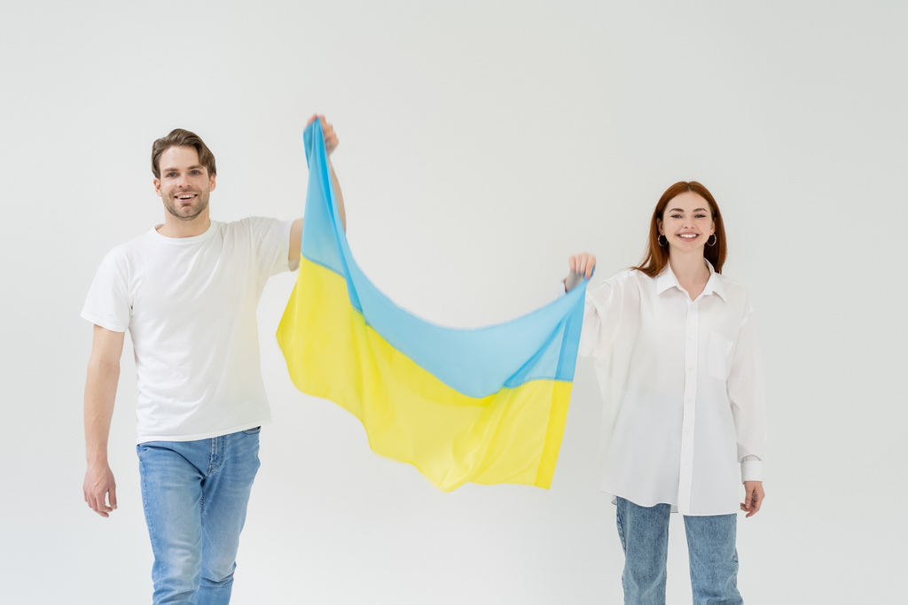 Wesoła młoda para trzymająca ukraińską flagę na białym tle  - Zdjęcie, obraz