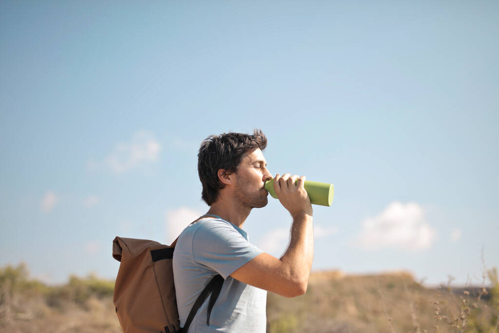Junger Mann trinkt aus einer Flasche - Foto, Bild
