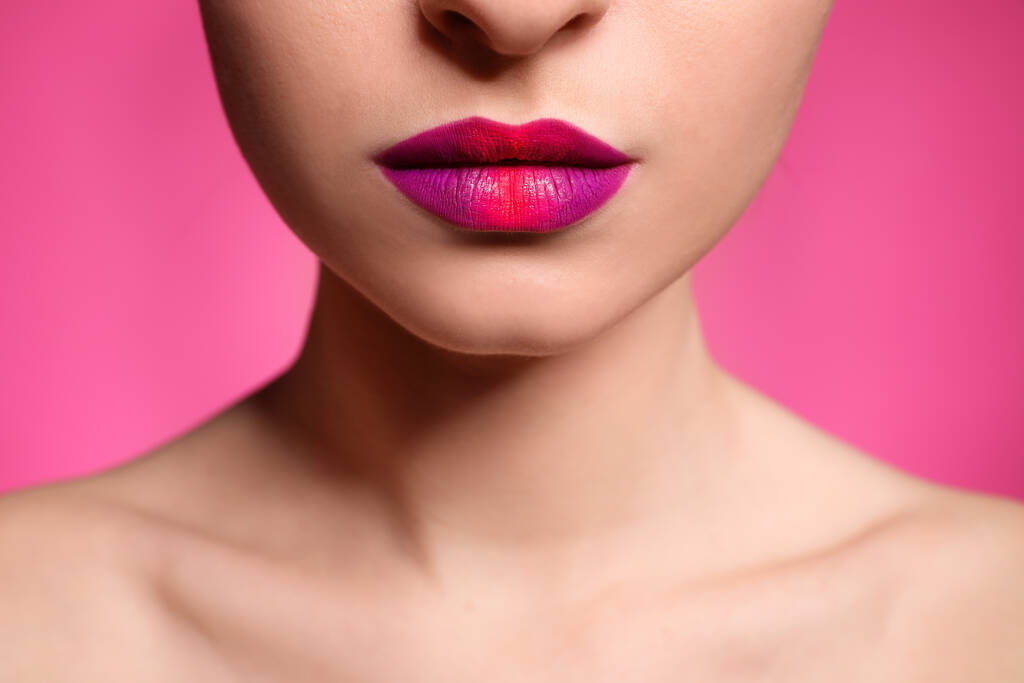 ピンクの背景に美しい唇の化粧を持つ若い女性,接写 - 写真・画像