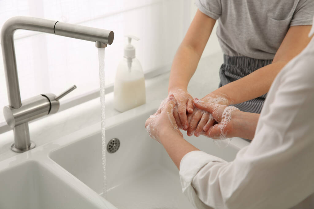 Мать и дочь мыли руки жидким мылом вместе дома, крупным планом - Фото, изображение
