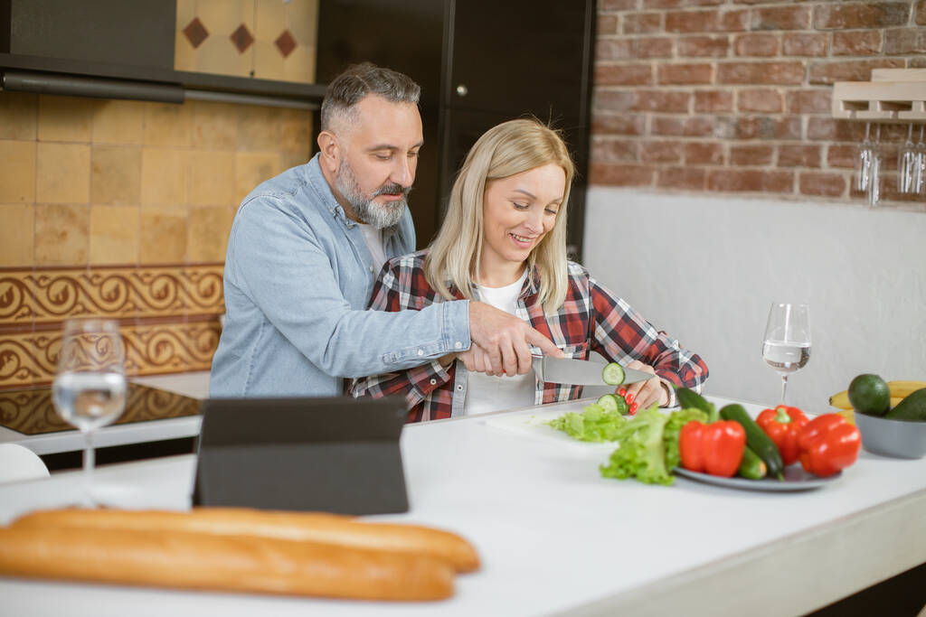 Keski-ikäinen perhe ruoanlaitto keittiössä ja käyttämällä tabletti - Valokuva, kuva