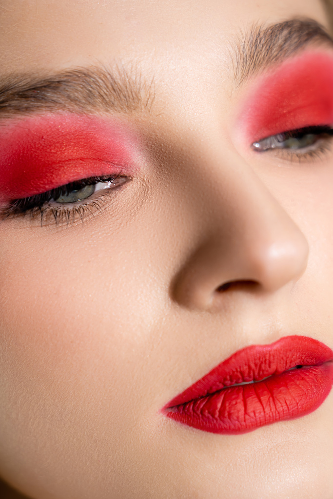 Close up view of young woman with red eye shadow and lips looking away  - Photo, Image