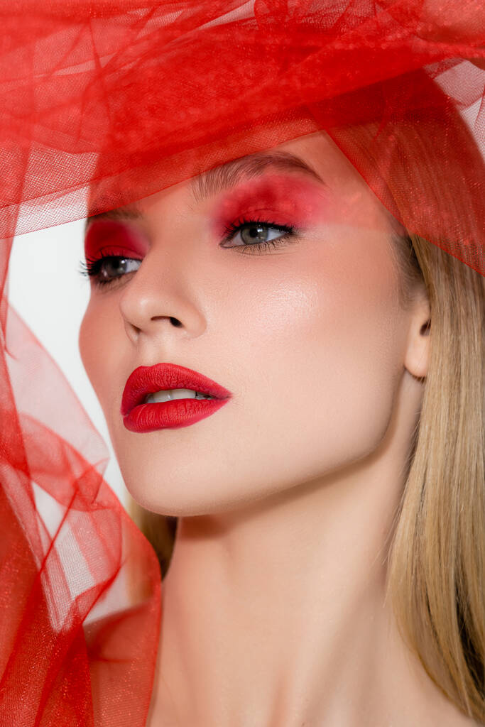 Retrato de modelo con labios rojos mirando hacia otro lado cerca de tela de tul aislada en gris  - Foto, imagen