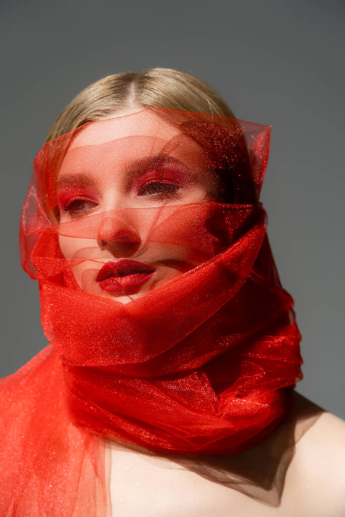 Woman with red lips wrapped in tulle fabric isolated on grey  - Photo, Image