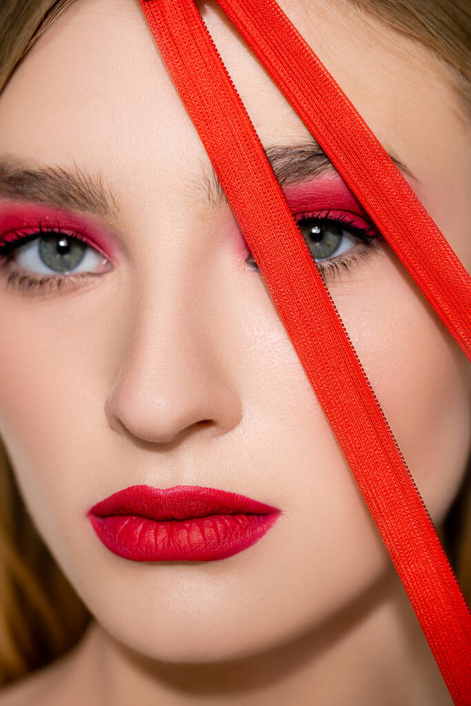 Close up view of model with red makeup looking at camera near zipper - Photo, Image