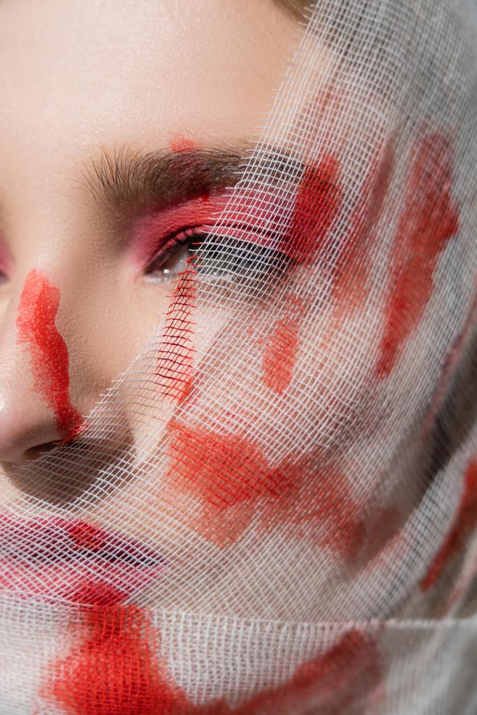 Vista recortada de la mujer con impresión roja de la mano en el vendaje médico en la cara mirando hacia otro lado  - Foto, imagen