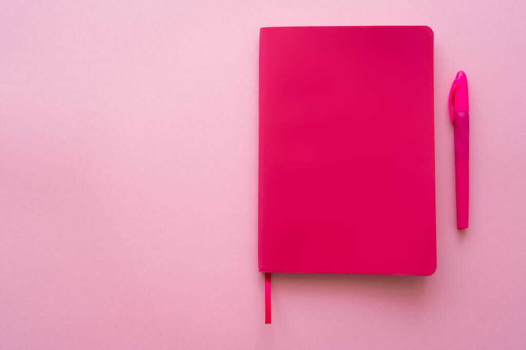 вид сверху на яркий ноутбук и ручку на розовый  - Фото, изображение