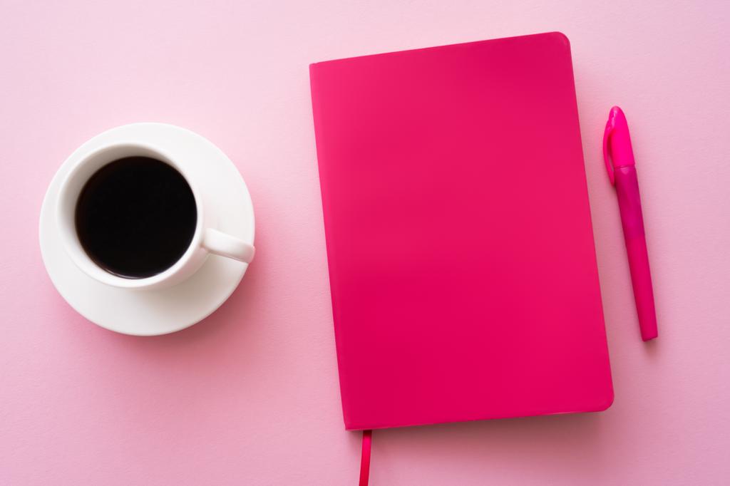 top view of pen near bright notebook and cup of coffee on pink  - Fotó, kép
