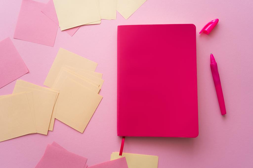 top view of pen near bright notebook and paper notes on pink  - Foto, Imagen
