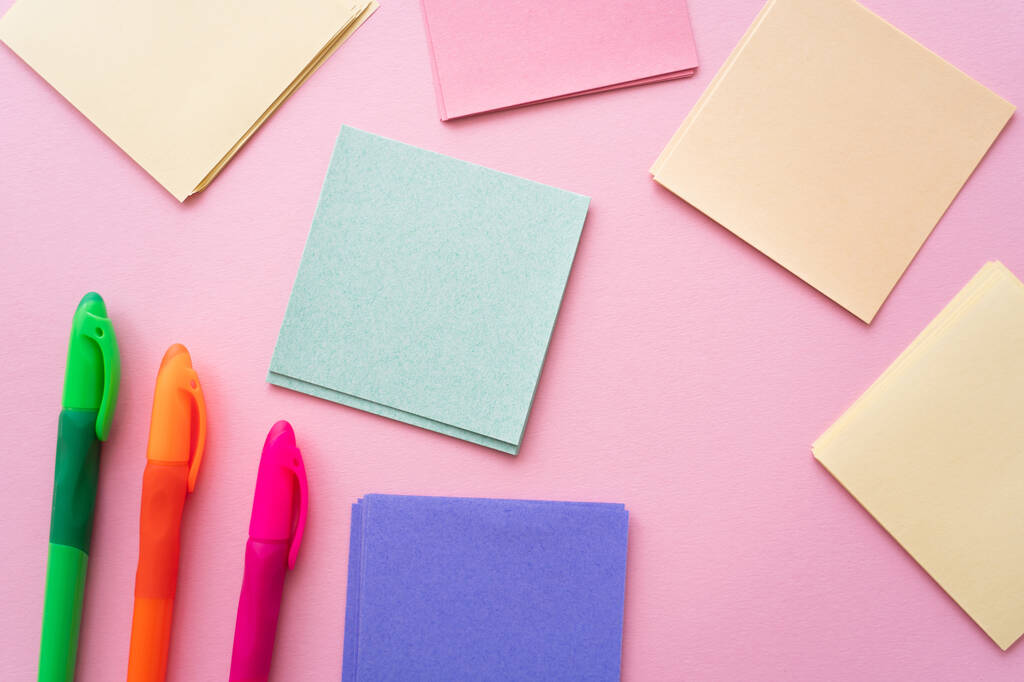 vista superior de canetas coloridas perto de notas de papel em branco em rosa - Foto, Imagem