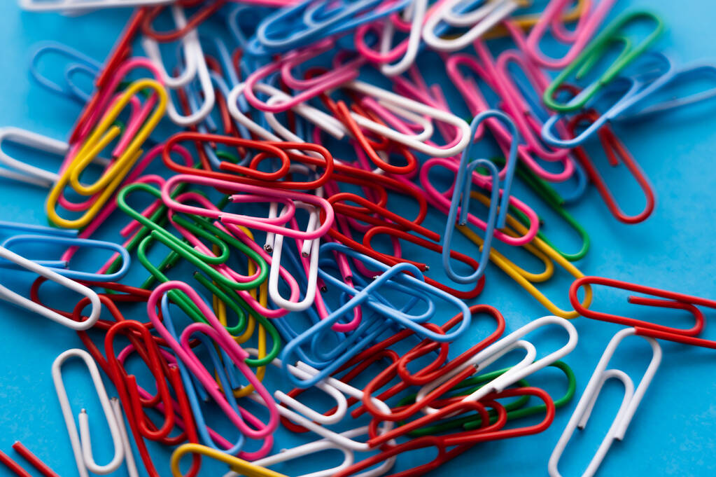 close up view of colorful paper clips on blue - Foto, afbeelding
