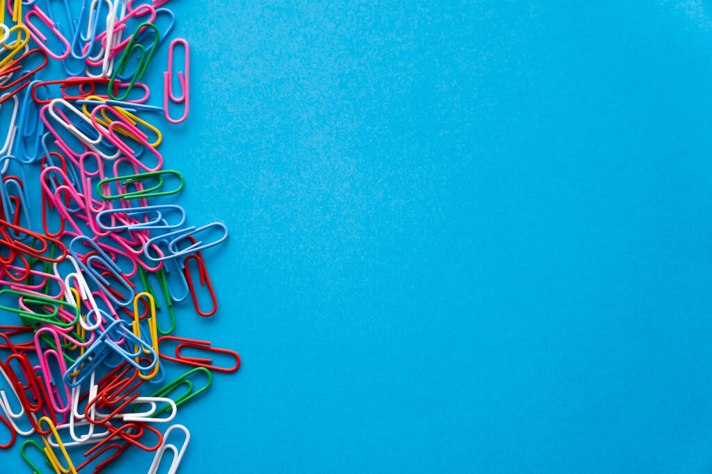 top view of colorful paper clips on blue - Fotó, kép