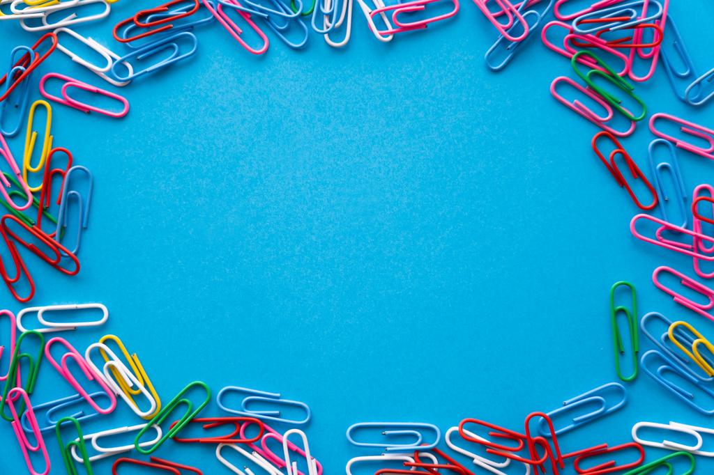 top view of frame with colorful paper clips on blue - Foto, afbeelding