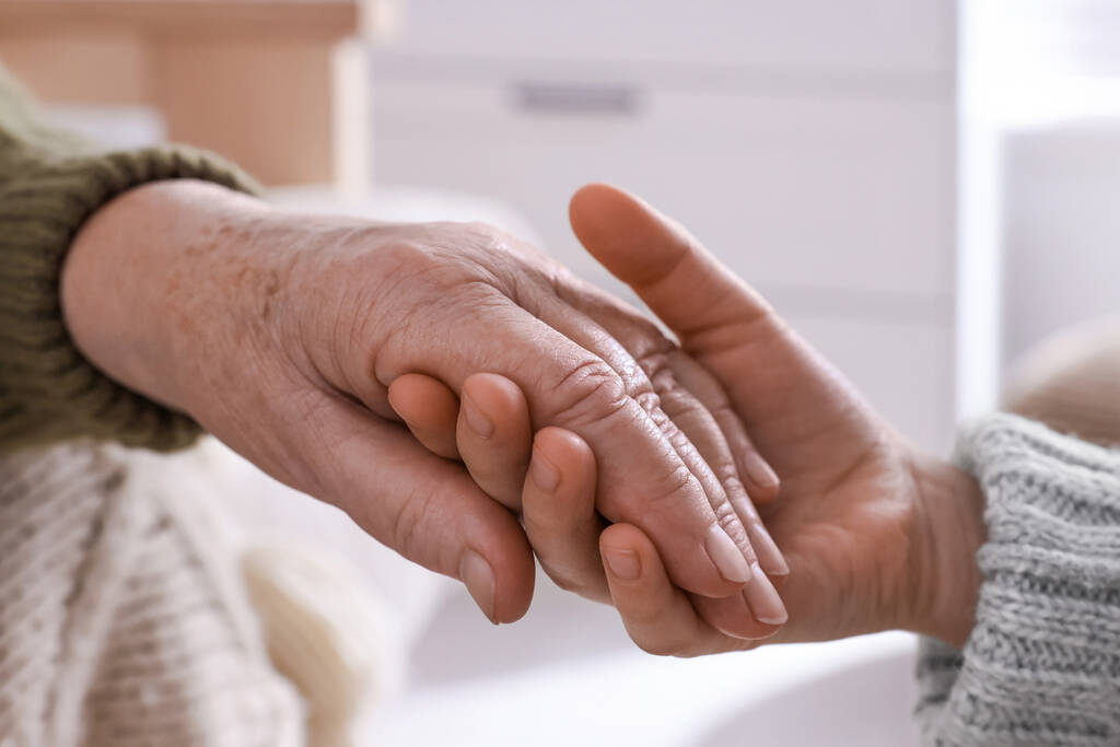Young and elderly women holding hands together indoors, closeup - Photo, Image
