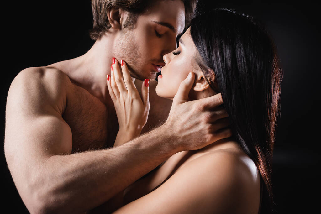 М'язистий чоловік цілує молоду дівчину ізольовано на чорному
  - Фото, зображення