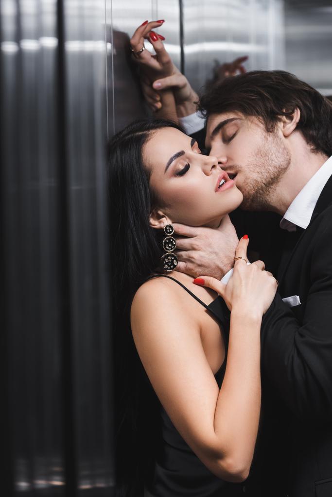 Hombre sexy besándose y tocando el cuello de novia seductora en ascensor  - Foto, Imagen