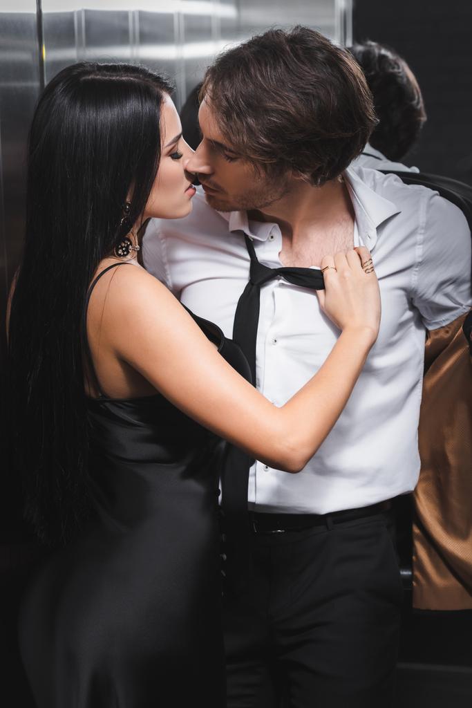 Szexi férfi leveszi a kabátját és csókolózik a barátnőjével a liftben  - Fotó, kép