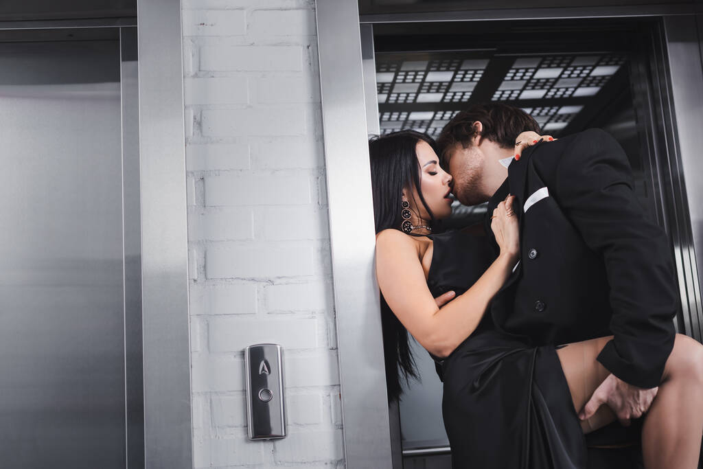 Sexy young couple in formal wear kissing near elevator  - Photo, Image