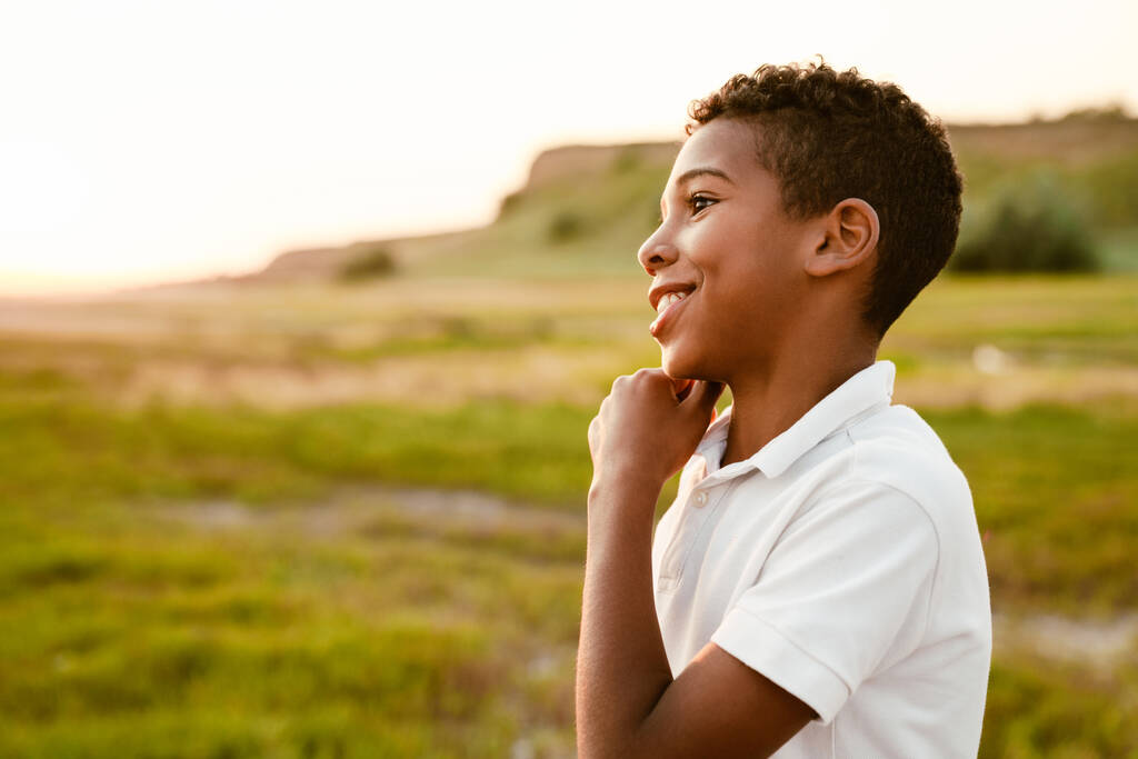 Black boy wearing white shirt smiling and looking aside outdoors - Photo, Image