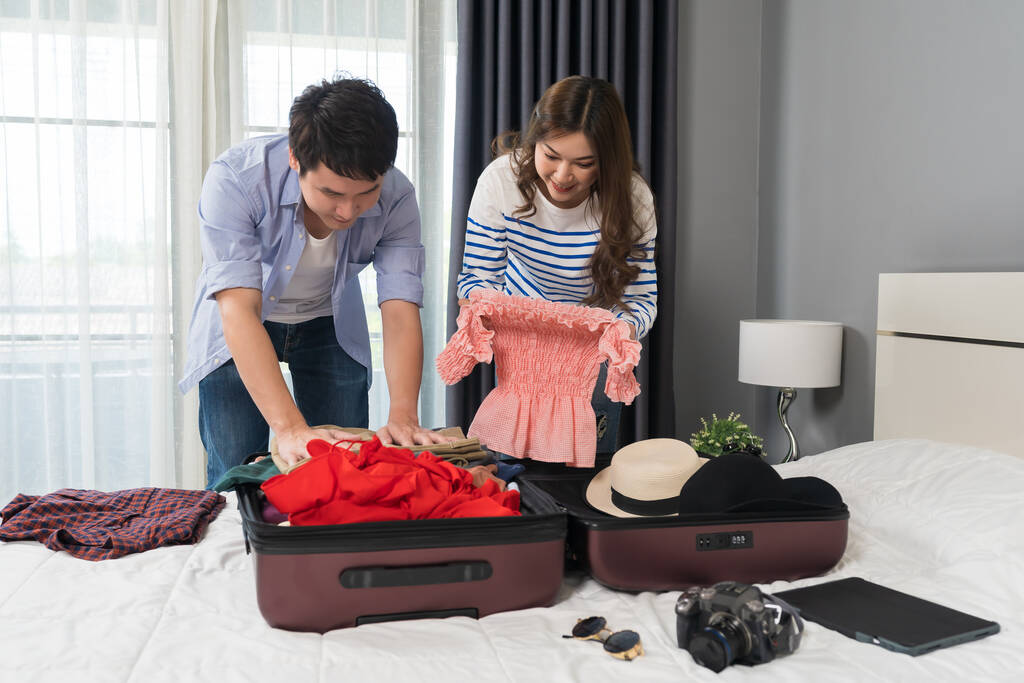 couple preparing and packing clothes into suitcase on a bed at home, holiday travel concept - Foto, imagen