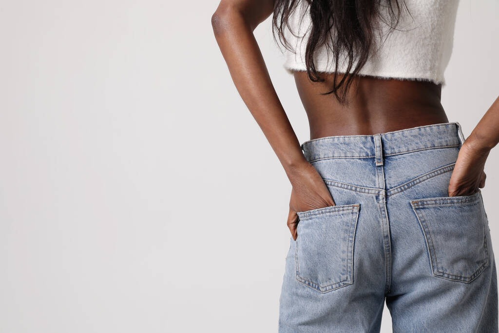 Mock-up of young Black woman wear blue jeans and top isolated on gray wall. - 写真・画像