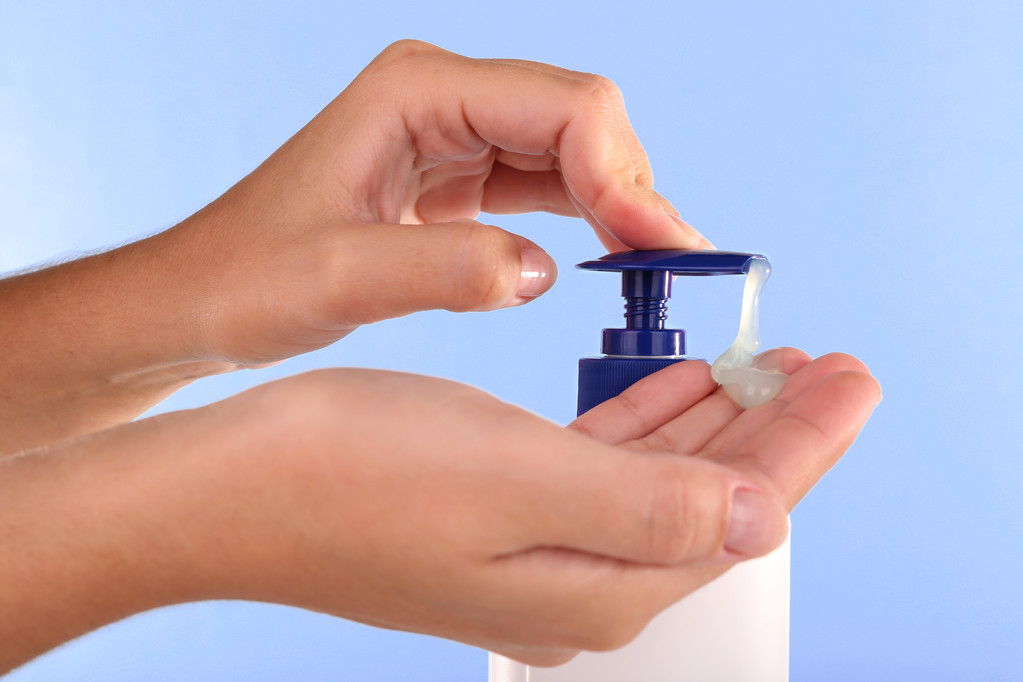 Vrouwelijke handen met behulp van vloeibare zeep op lichte blauwe achtergrond - Foto, afbeelding
