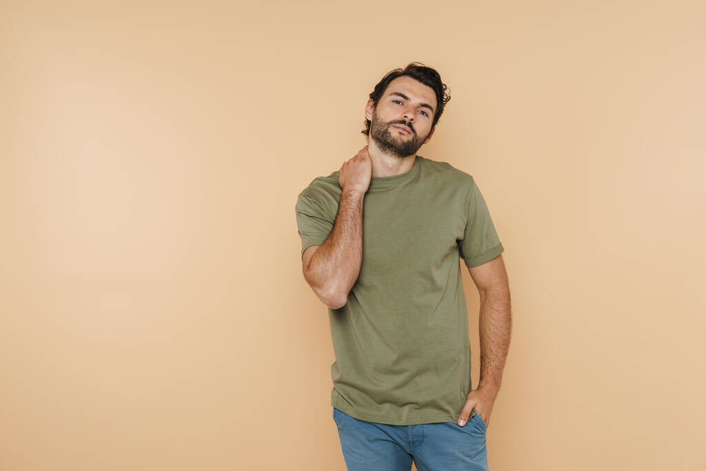White bristle man wearing t-shirt posing and looking at camera isolated over beige background - Foto, Imagem