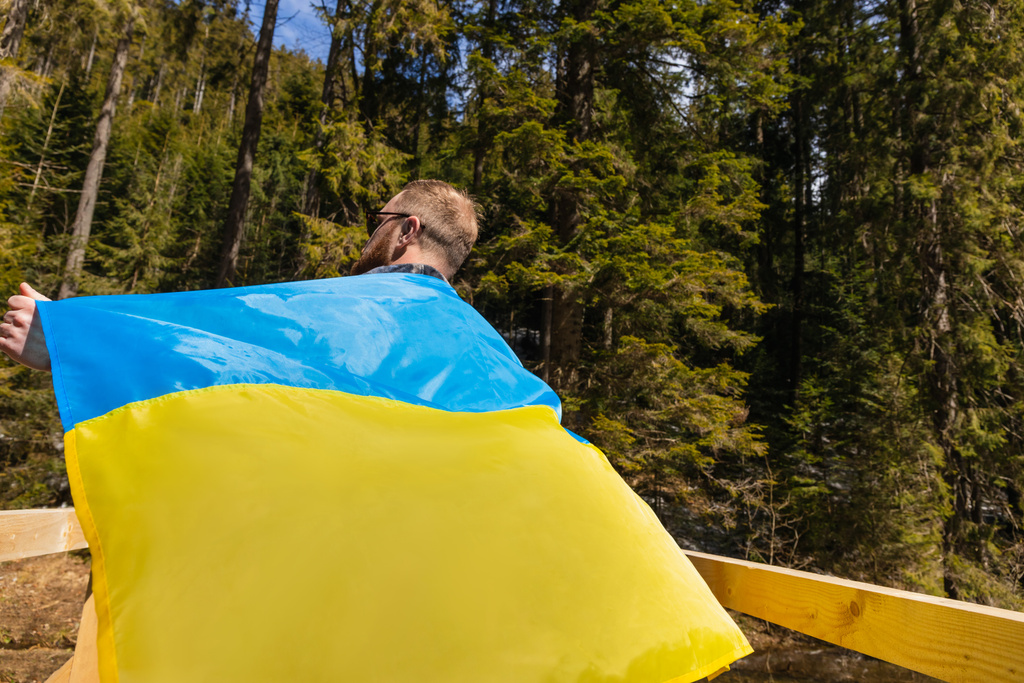 Mann mit ukrainischer Flagge im grünen Wald  - Foto, Bild