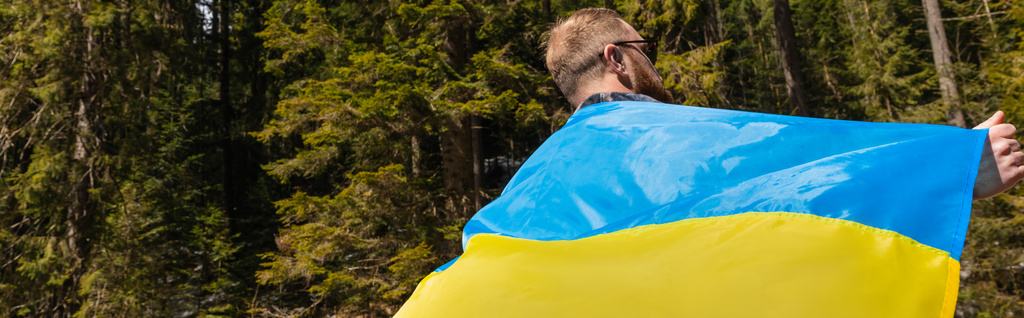 Uomo con bandiera ucraina nella foresta, striscione  - Foto, immagini