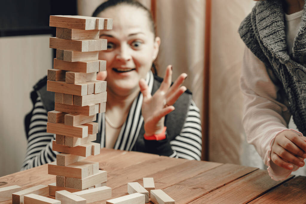 Mom and daughter play a board game, build a tower from wooden blocks. - Photo, Image