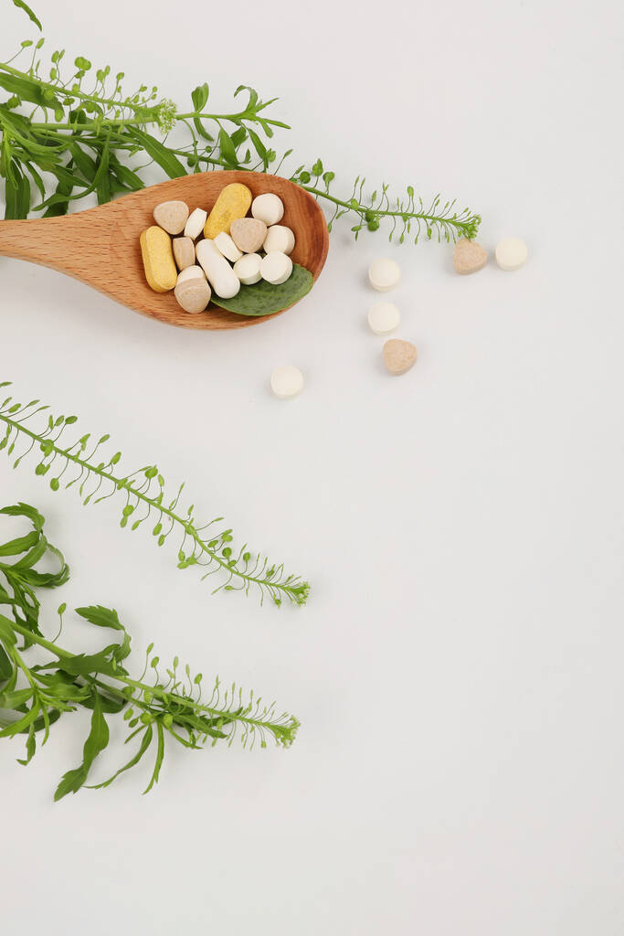 uma colher de madeira e uma pílula, fundo branco, foto conceito criativo médico - Foto, Imagem