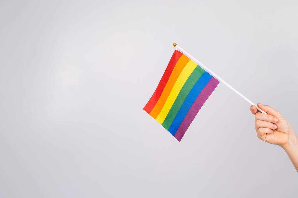 Eine Frau hält eine Regenbogenfahne auf weißem Hintergrund. - Foto, Bild