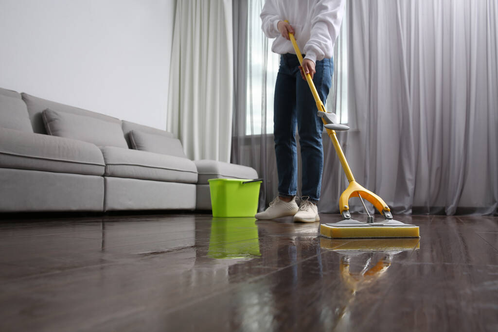Mulher limpeza piso em parquet com esfregão dentro de casa, close-up - Foto, Imagem