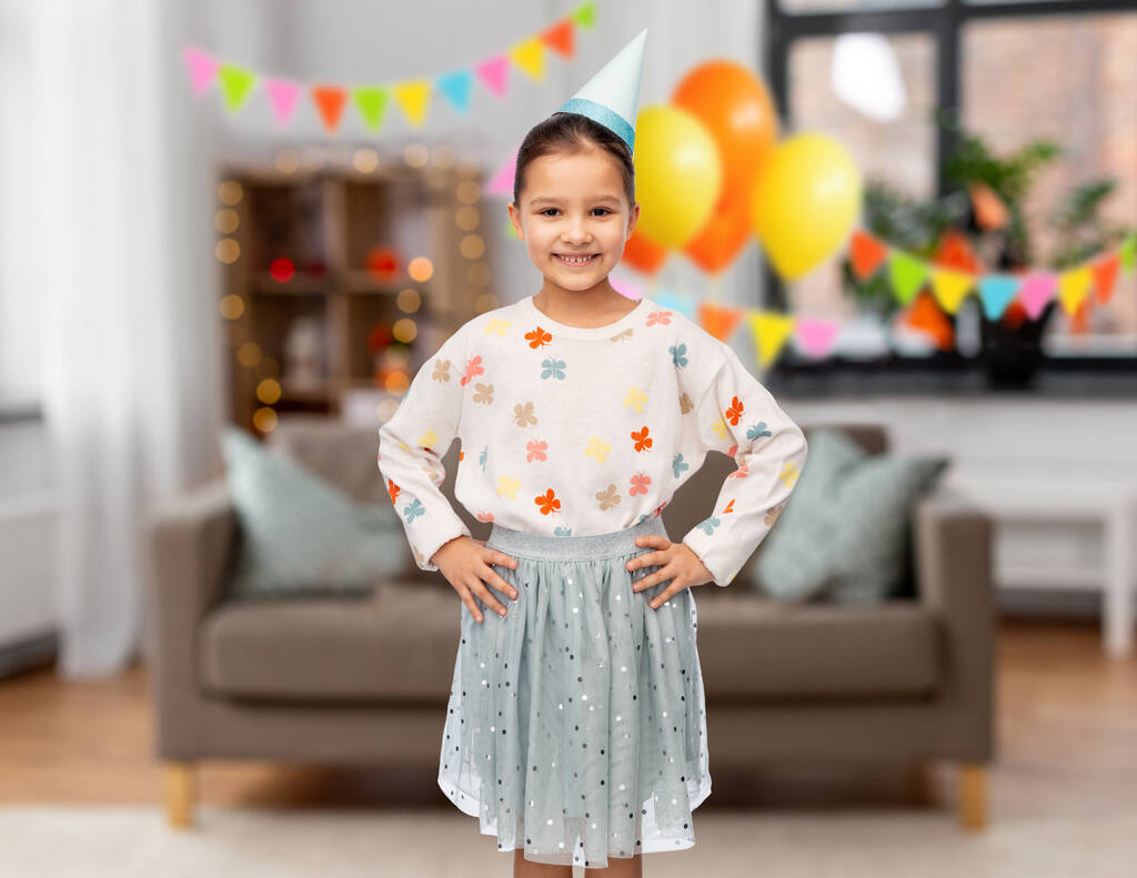 glimlachend klein meisje in verjaardagsfeestmuts - Foto, afbeelding