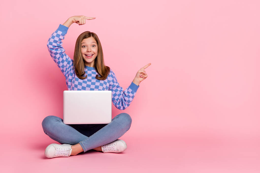 Full length photo of blond little girl with laptop indicate promo wear sweater jeans footwear isolated on pink background - Foto, Imagem